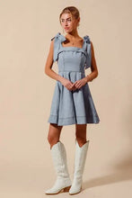 Light blue denim dress with diamond bow ribbon details on shoulders and a square neckline in fit and flare style