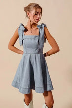 Light blue denim dress with square neckline and tied diamond bow ribbon shoulder accents in a fit and flare style
