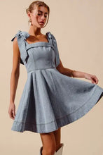 A light blue denim dress with a square neckline, tied bow ribbon shoulders, and subtle diamond bow star embroidery