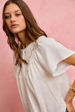 White cotton gauze blouse with lace trim around neckline and flutter sleeves in lightweight textured fabric