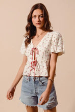 White ditsy floral print gauze blouse with red ribbon ties, puffed sleeves, and peplum hem by SO ME