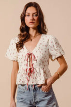 White ditsy floral print gauze tie-front blouse with short puffed sleeves and red ribbon peplum detail