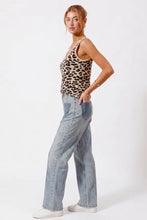 A woman wears a so me leopard print knit cami tank in beige and black paired with light-wash denim jeans