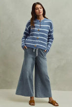 Blue and white horizontally striped knit cardigan with gold toned buttons paired with mid rise elastic waist flare jeans