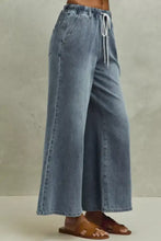 Light-wash denim flare jeans mid rise elastic waist with wide-leg fit and white drawstrings for comfortable wear