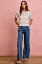 A white lace-knit short-sleeved top with diamond pattern paired with so me mid rise stretch denim jeans