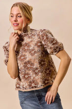 A brown and beige texture floral mesh top with short puffed sleeves and back button closure