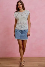 White lace knit sleeveless top with detailed pattern and ribbed neckline paired with washed denim mini skirt with contrast pockets
