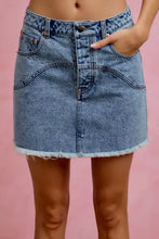 A mid-waisted washed denim mini skirt with contrast floral pockets and a frayed hem in classic stitching details