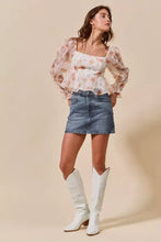 White cowboy boots with low block heel and subtle stitching paired with so me washed denim mini skirt with pockets