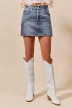 White cowboy boots with stitched floral embroidery and wooden block heels paired with a washed denim mini skirt with pockets