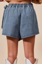 Light-wash denim skort with elastic waistband and wrap braided trimmed side tie detail in denim material