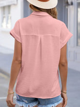 A soft pink cuffed short sleeve blouse with subtle textured fabric and relaxed fit in solid color design