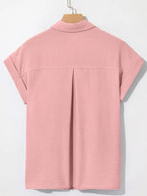 A soft pink cuffed short sleeve shirt with subtle textured fabric and classic collar ideal for casual wear