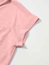 A soft pink solid color cuffed short sleeve shirt with subtle textured fabric and neatly folded cuffs