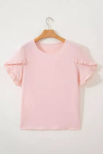 A soft pink lightweight short sleeve blouse with ruffle trim and a simple round neckline for elegant wear