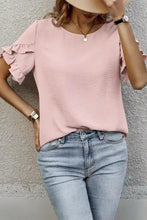 A soft pink short sleeve blouse with ruffle trim and relaxed fit perfect for casual or office wear
