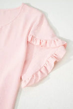 A soft pink solid color short sleeve blouse with delicate ruffle trim and lightweight fabric for elegant wear
