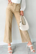 White crescent-shaped handbag with braided leather straps and metallic hardware paired with solid color seamed wide leg cropped jeans