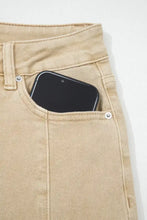 A black smartphone in the front pocket of beige solid color seamed center wide leg cropped denim jeans