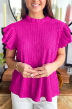 A vibrant fuchsia textured ruffle short sleeve blouse with pleated fabric and ruffled sleeves in a high neckline
