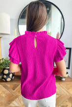 A vibrant fuchsia solid color textured ruffle short sleeve blouse with pleats and a keyhole back detail