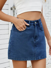 A mid-rise solid mini denim skirt in medium blue wash with visible stitching and front pockets