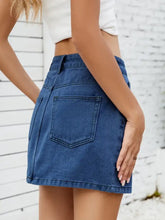 A mid-rise solid mini denim skirt in medium blue wash with a front patch pocket and clean stitching