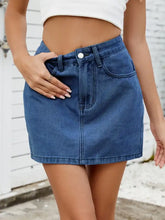 A mid-rise solid mini denim skirt in medium blue wash with button closure and front pockets