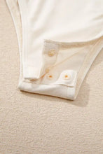 Cream-colored stretchy sequin long sleeve bodysuit with three matching button closures on a folded hem