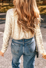 A shimmering gold sequin long sleeve fitted bodysuit with a slightly cropped silhouette for elegant wear