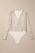 A shimmering silver sequin long sleeve bodysuit with a white underlayer perfect for elegant occasions