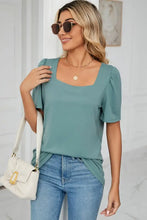 Woman in square neck puff sleeve top and jeans with white bag