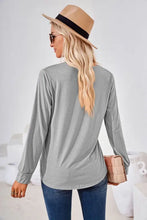Woman in square neck ruched long sleeve blouse, tan hat, jeans