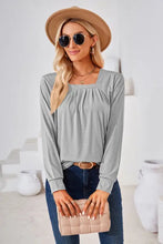 Woman in square neck ruched long sleeve blouse with jeans and beige hat
