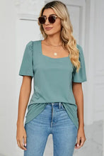 Woman in square neck short sleeve t-shirt with puffed shoulders and light blue jeans