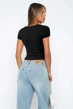 Woman in black square neck short sleeve tee, light jeans, white bag