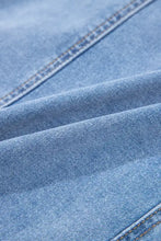 Blue denim fabric with visible stitching and textured weave of a square neck wide strap denim dress