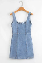 Light blue denim dress with square neck wide strap design hanging on a wooden hanger