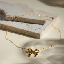 Gold-tone stainless steel bow pendant necklace with beaded chain