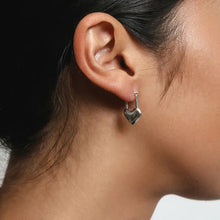 Stainless steel heart lock drop earring on woman’s ear