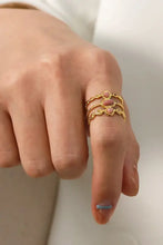 Stainless steel open ring with three gold rings and pink oval stones on finger