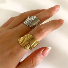 Two stainless steel textured wave rings on fingers, gold and silver tones