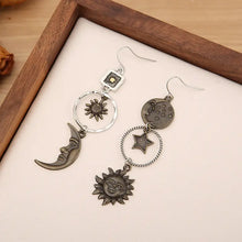 Mismatched silver-tone moon earrings with celestial star and sun designs