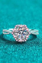 Sterling silver crisscross ring with pink halo and diamond on green background