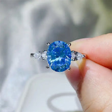 Sterling silver ring with oval blue gemstone and pear moissanite accents