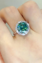 Sterling silver ring with oval green gemstone and clear halo