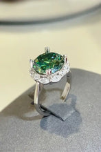 Sterling silver ring with oval green gemstone and clear halo stones