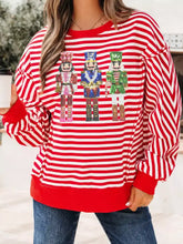Red and white striped long-sleeved casual holiday sweater with three sequined nutcracker figures and care instructions