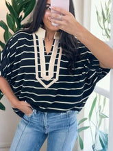 Black and cream striped blouse with collar v neck highlighted by cream-colored embroidered trim and elastic cuffs